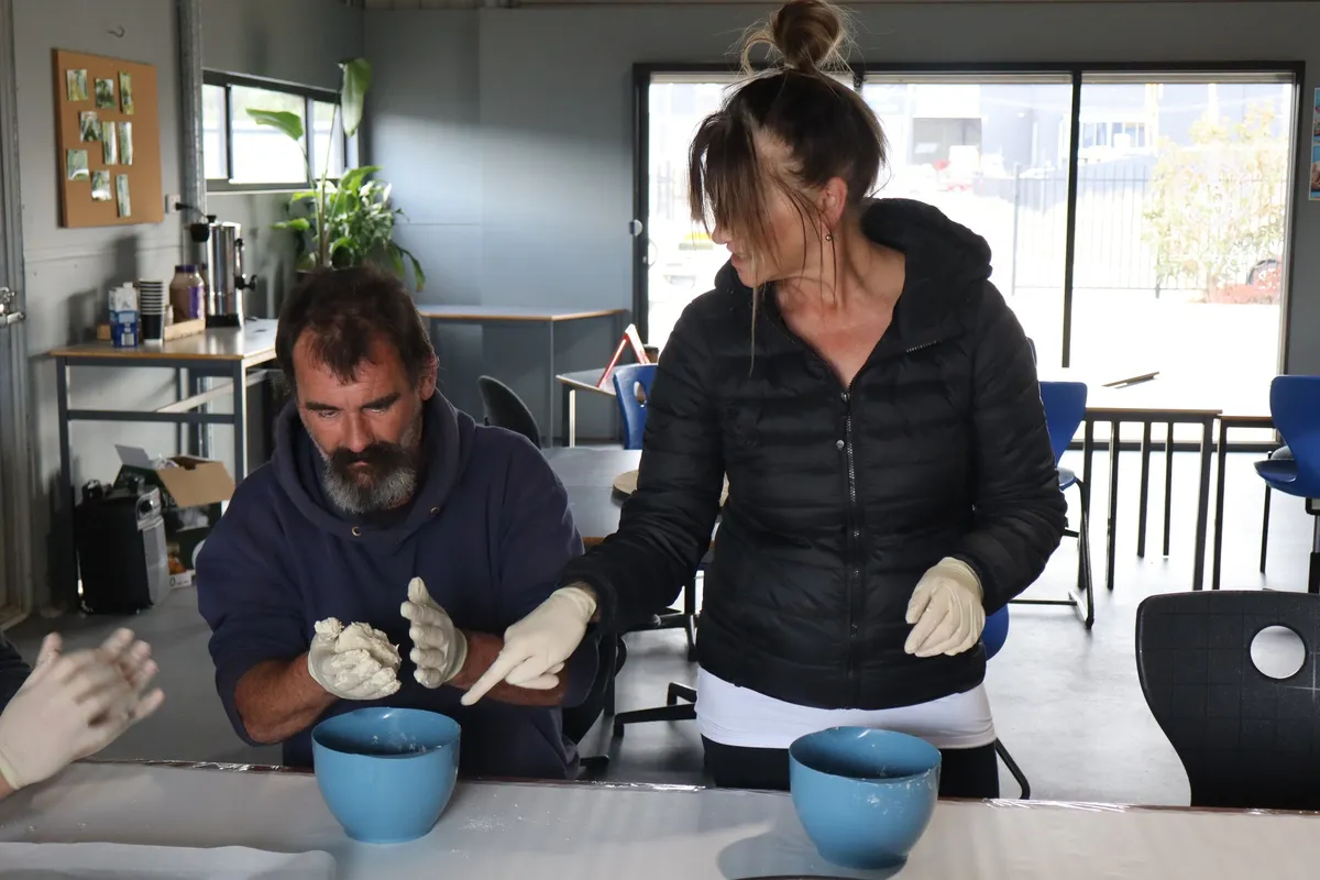 two people wearing gloves working with blue ceramic bowls on a table