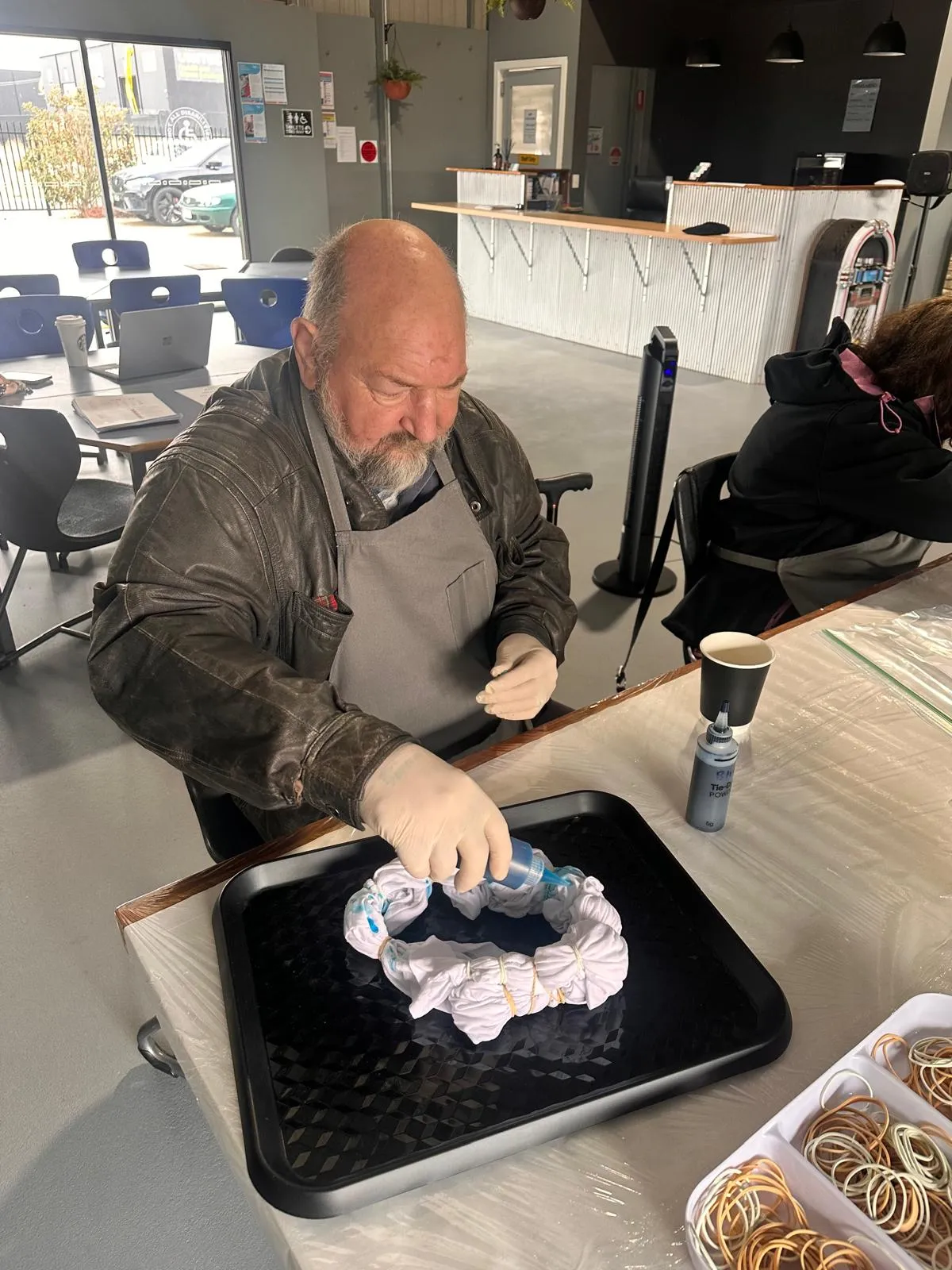 man creating tie-dye pattern on fabric with blue dye and rubber bands